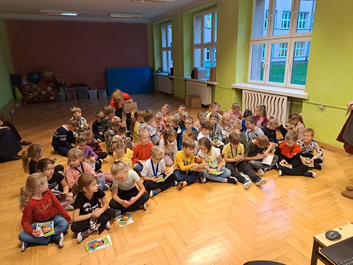 Dzieci siedzą na podłodze i słuchają o segregacji odpadów